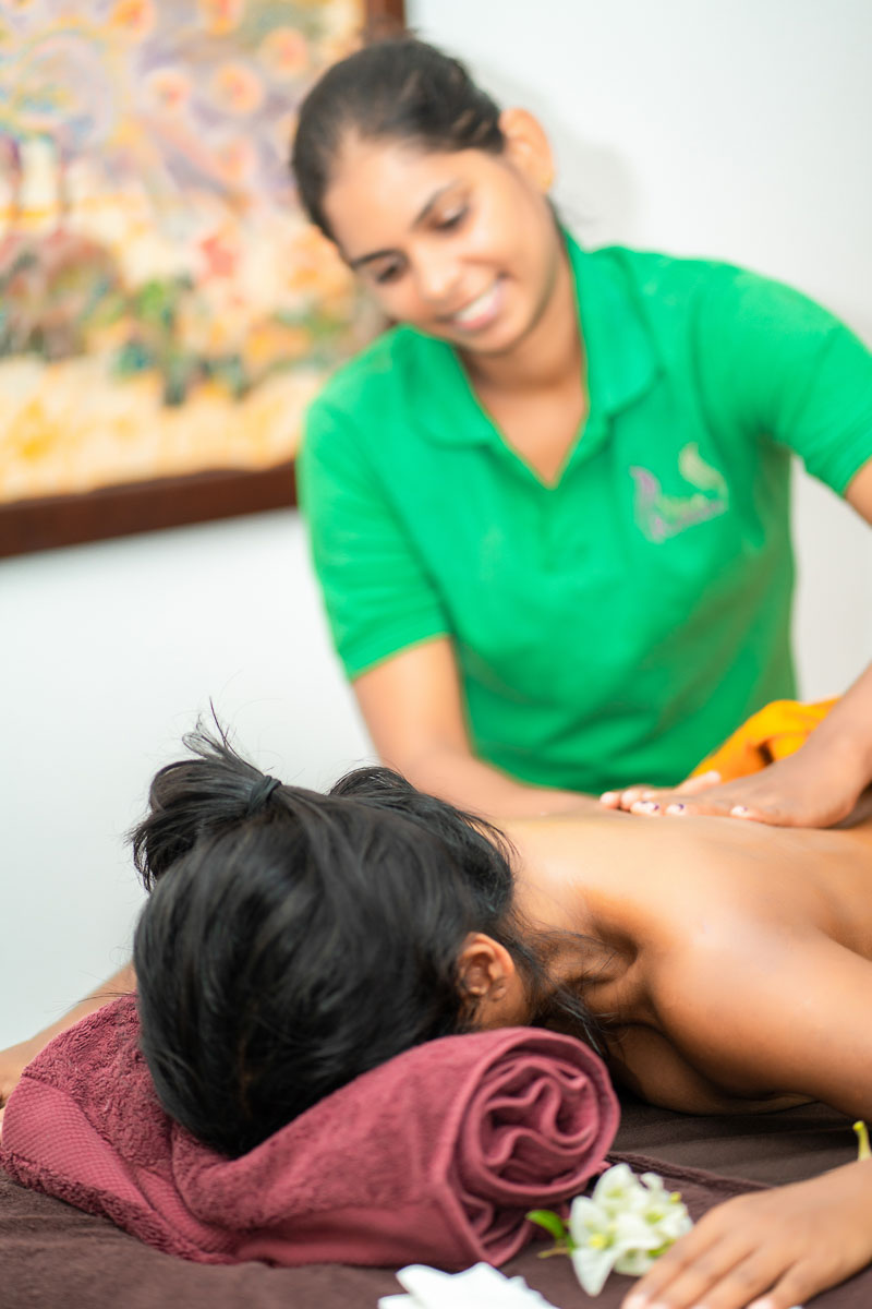 Ayurveda-Kur Massage: Therapeutin im Hintergrund bei der Rueckenmassage
