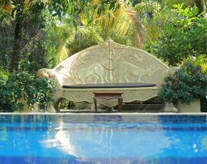 Steinbank mit Buddhistischen Skulpturen beim Pool im Garten